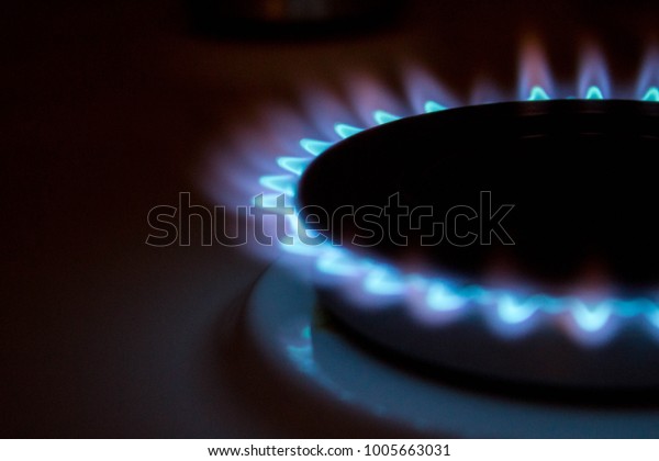 A\
bright neon blue flame emitting from a cooker\
hob.