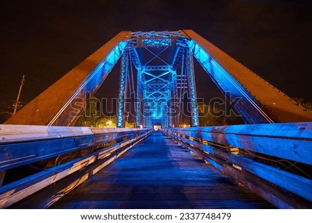 Bright neon blue lights on wooden walking bridge inside truss railroad bridge at night in Ohio