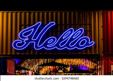 A Bright Neon Hello Sign Above A Doorway Lights Up The Entrance To A Busy Building