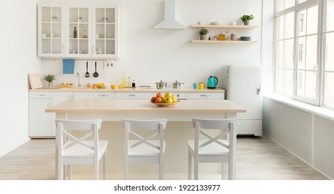 Bright new kitchen and Scandinavian home interior. White furniture with utensils, colored cups and kettle, shelves with dishes and plants in pot, refrigerator in dining room, panorama, empty space