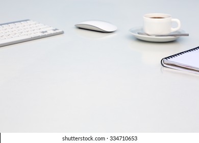 Bright Open Space Office White Table Angle View with Coffee Mug Opened Blank Notepad and Computer Keyboard and Mouse on Desk Side View with Reflections and Copy Space