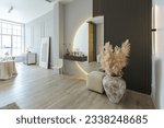 bright open-plan apartment in a modern design, light walls and wooden floor. stylish entrance hall with a beautiful vase and a round mirror and a sofa for guests