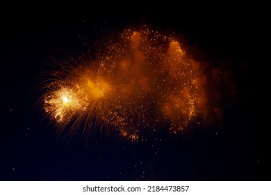 Bright orange glowing fireworks with sparks flying sideways against the night sky. High quality photo
