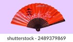 Bright orange Japanese hand fan featuring a cherry blossom and pagoda design, isolated on a pastel background