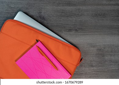 Bright Orange Laptop Case With Pink Note Book And Pen Flatlay