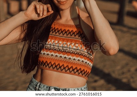 Bright orange patterned crop top and vintage jeans on a tanned female body, youth, freedom and summer fashion outfit