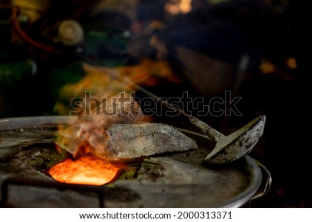 Bright orange and red tones of super heated mix of metals tin and copper in special furnace construction. Bronze casting process and manual labor concept.