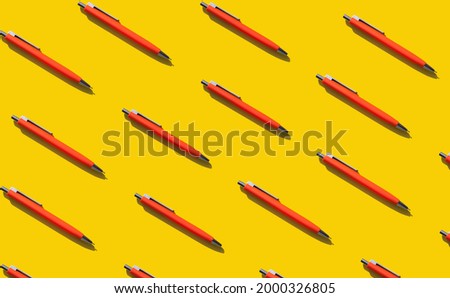 Bright orange repeating pens on a yellow background. Concept for learning, literature, writing texts