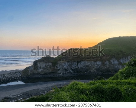 Bright orange sunset hiding behind cliff face