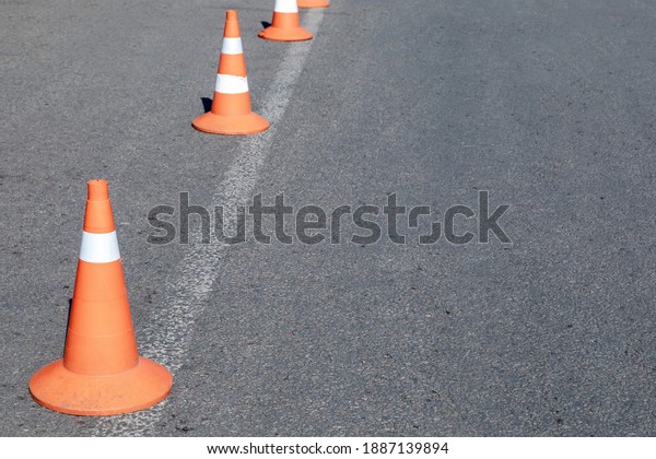 Bright orange\
traffic cones on asphalt road. Traffic signal cones are considered\
universal products, with their help you can quickly and easily\
ensure the safety of all\
road