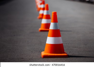 conos de tráfico naranja brillante parados en fila sobre asfalto oscuro