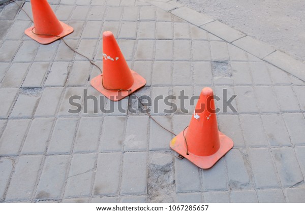 bright orange traffic cones standing in a row on\
dark asphalt