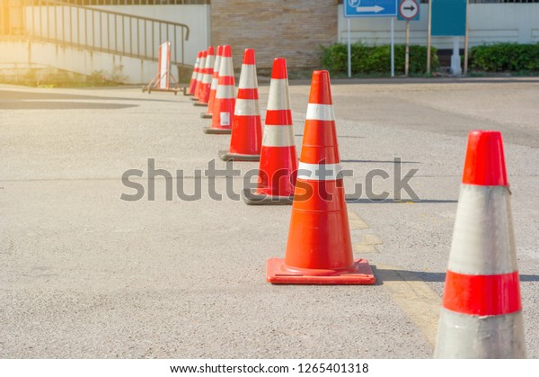 bright\
orange traffic cones standing in a row on asphalt\

