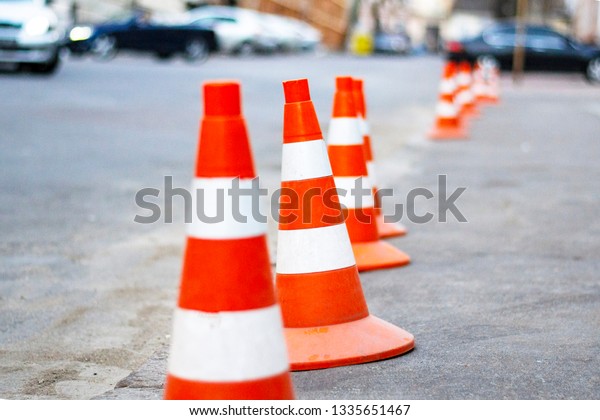 bright
orange traffic cones standing in a row on 
asphalt