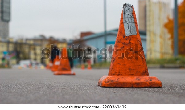Bright\
orange traffic cones standing in a row on the dark asphalt. Orange\
cones on the asphalt prohibit the passage of\
cars.