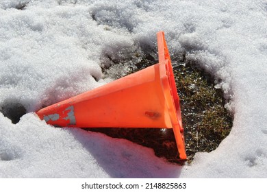 Bright Orange Traffic Pylon In The Snow And Grass