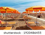 Bright orange umbrellas and sun loungers on the beach in Rimini, Italy. 