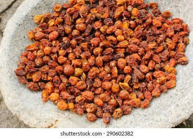 Bright orange and yellow dried sea buckthorn (Hippophae rhamnoides) berries close-up in a grey stone bowl. A healthy snack and alternative herbal medicinal product. Perennial shrub. Natural background