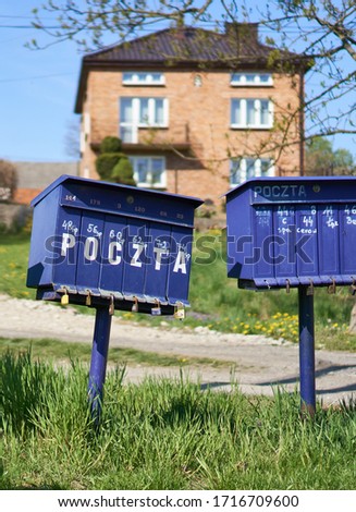 Bright outdoor cluster mail boxes with individual slots in rural Poland. The text in Polish on the mailbox translates to: 'The post office of Poland'                               