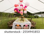 Bright paper lanterns hanging inside a wedding tent with colorful table settings.