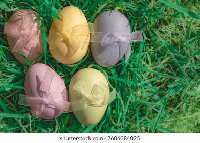 Bright, pastelcolored Easter eggs beautifully adorned with cheerful bows, resting on vibrant green grass