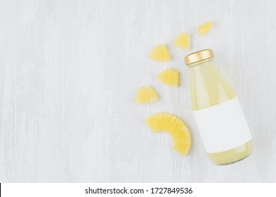 Bright Pinapple Yellow Juice In Glass Bottle With Blank Label, Sliced Fruit On White Wooden Board, Top View, Copy Space, Template For Design, Advertising, Portfolio.