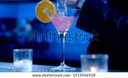bright pink cocktail with orange slice
