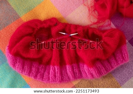 Bright pink and red mohair yarn hand knitted sweater with stitches including stocking stitch and rib, knitted on circular needles. 