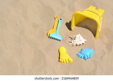 Bright plastic bucket and rakes on sand. Beach toys. Space for text - Shutterstock ID 2184964859