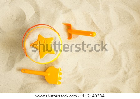 Bright plastic children's toys in the sand. Concept of beach recreation for children. Top view. Space for text. Flat lay, top view, copy space