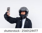 Bright portrait of a cheerful female motorcycle delivery rider capturing a selfie to send to a customer. Wearing safety gear. Set against a clean white background for clarity and impact.