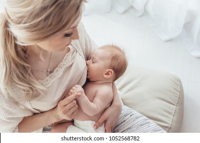 Bright portrait of a mom breast feeding baby over window lighting.