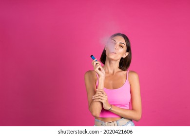 Bright Portrait Of Young Beautiful Woman On Pink Background Smoking Electronic Cigarette, Enjoying, A Lot Of Smoke