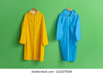 Bright raincoats hanging on green wall