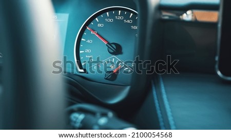 Bright red arrow on speedometer located on dashboard of car goes up showing increasing of auto speed and indicator shows petrol level, closeup