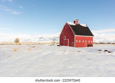 A bright red barn against a blue sky and winter landscape. - Powered by Shutterstock