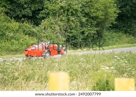 a bright red bugatti type 35B replica open-top sports car, 1971 volkswagen 1285cc underpinnings, driven through countryside