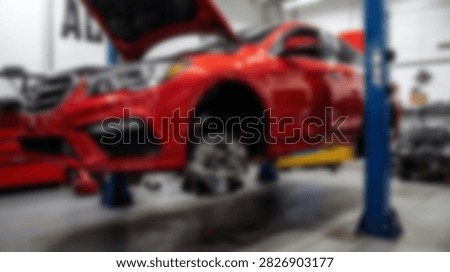 A bright red car is elevated on a hydraulic lift inside a clean and well-lit automotive service center, indicating repair or inspection work.