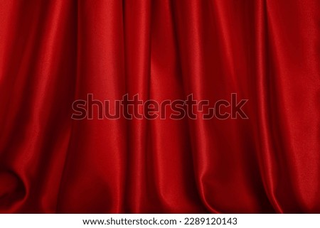 Bright red curtains are beautifully wavy, close-up.