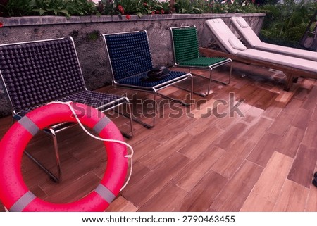 Bright red donut pool float resting on patterned tiles by a luxurious swimming pool, ready for summer relaxation.