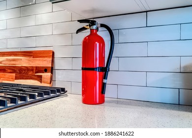 Bright Red Fire Extinguisher Against White Tile Backsplash Inside Home Kitchen