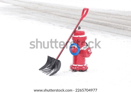 Bright red fire hydrant with shovel in the snow. Clearing snow from a fire hydrant. White space for text.