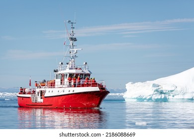 Bright Red Fishing Ship Carrying Tourists In Among Large Icebergs In The Ilulissat Icefjord, Greenland On 17 July 2022