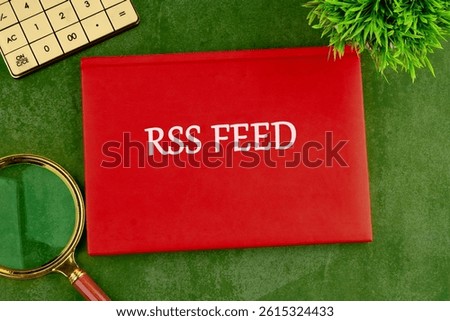 A bright red folder labeled RSS FEED is positioned on a green background alongside a magnifying glass and a calculator, showcasing the exploration of RSS feeds.