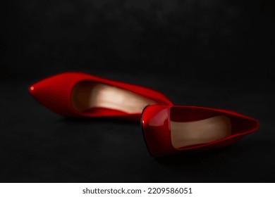 bright red high-heeled shoes lie on a dark background, selective focus