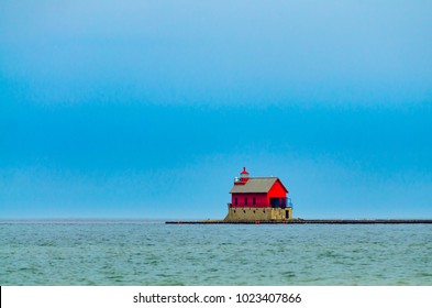 The bright red lighthouse in Grand Haven, Michigan, shown in contrast against dark storm clouds and the blue-green waters of Lake Michigan