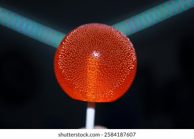 A bright red lollipop with tiny bubbles inside on a dark background. High quality photo