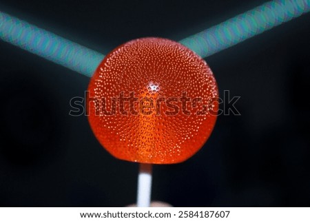A bright red lollipop with tiny bubbles inside on a dark background. High quality photo