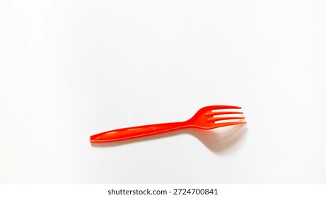 A bright red plastic fork is placed on a clean white surface. The minimalist top-down view highlights its vibrant color and functional design, perfect for takeaway and casual dining themes.