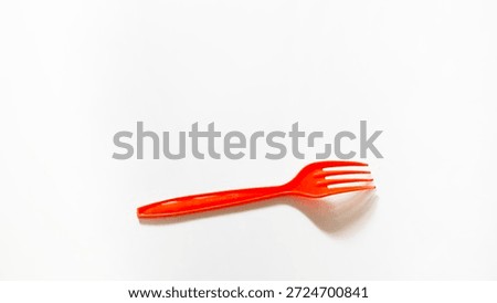 A bright red plastic fork is placed on a clean white surface. The minimalist top-down view highlights its vibrant color and functional design, perfect for takeaway and casual dining themes.